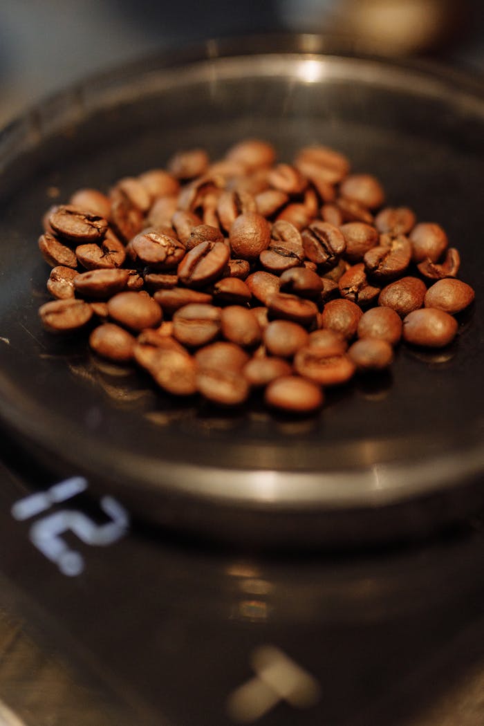 Roasted coffee beans piled on a digital scale for precise measurement.